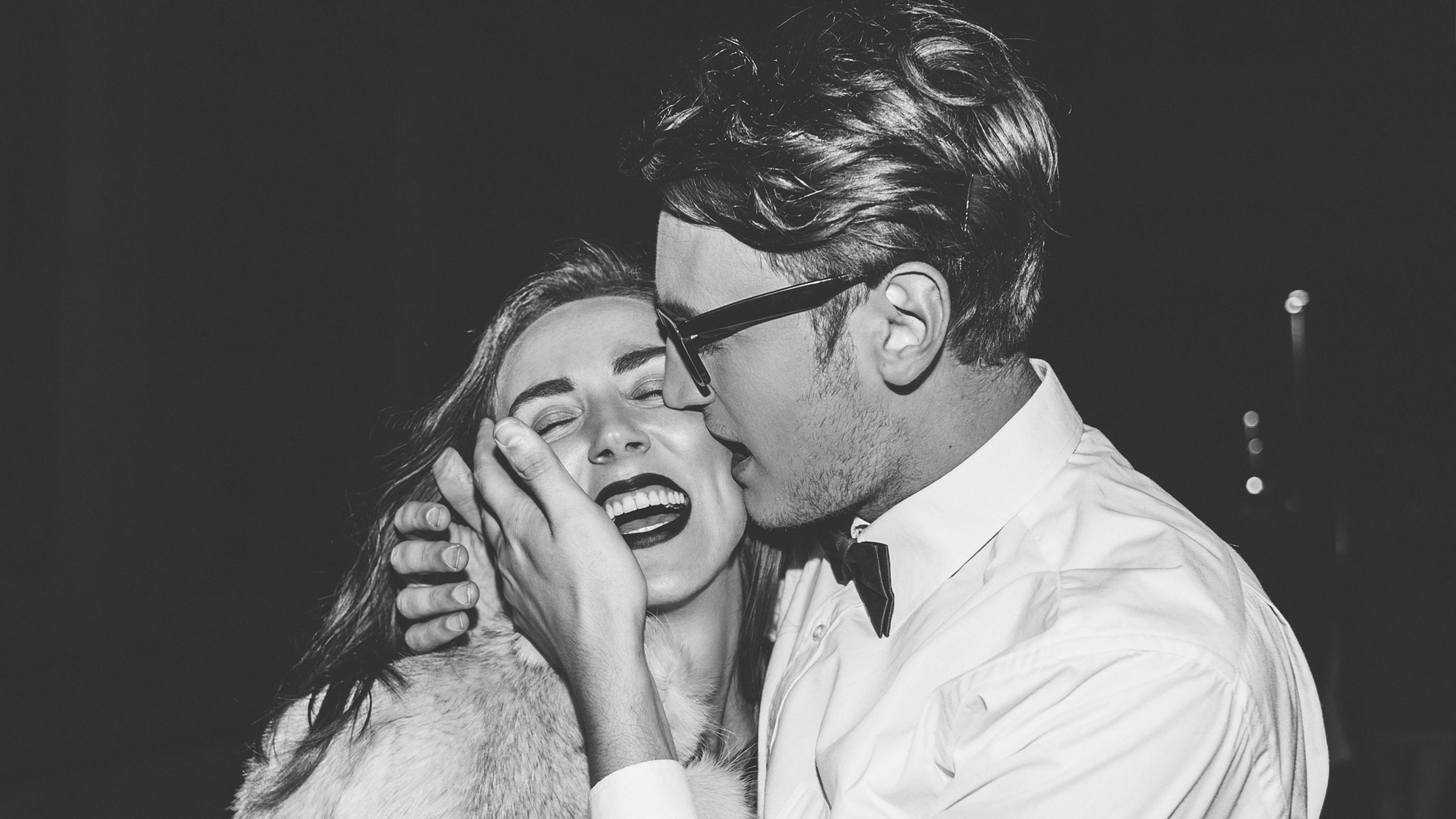 Black-and-white photo of a joyful couple laughing and embracing at night.