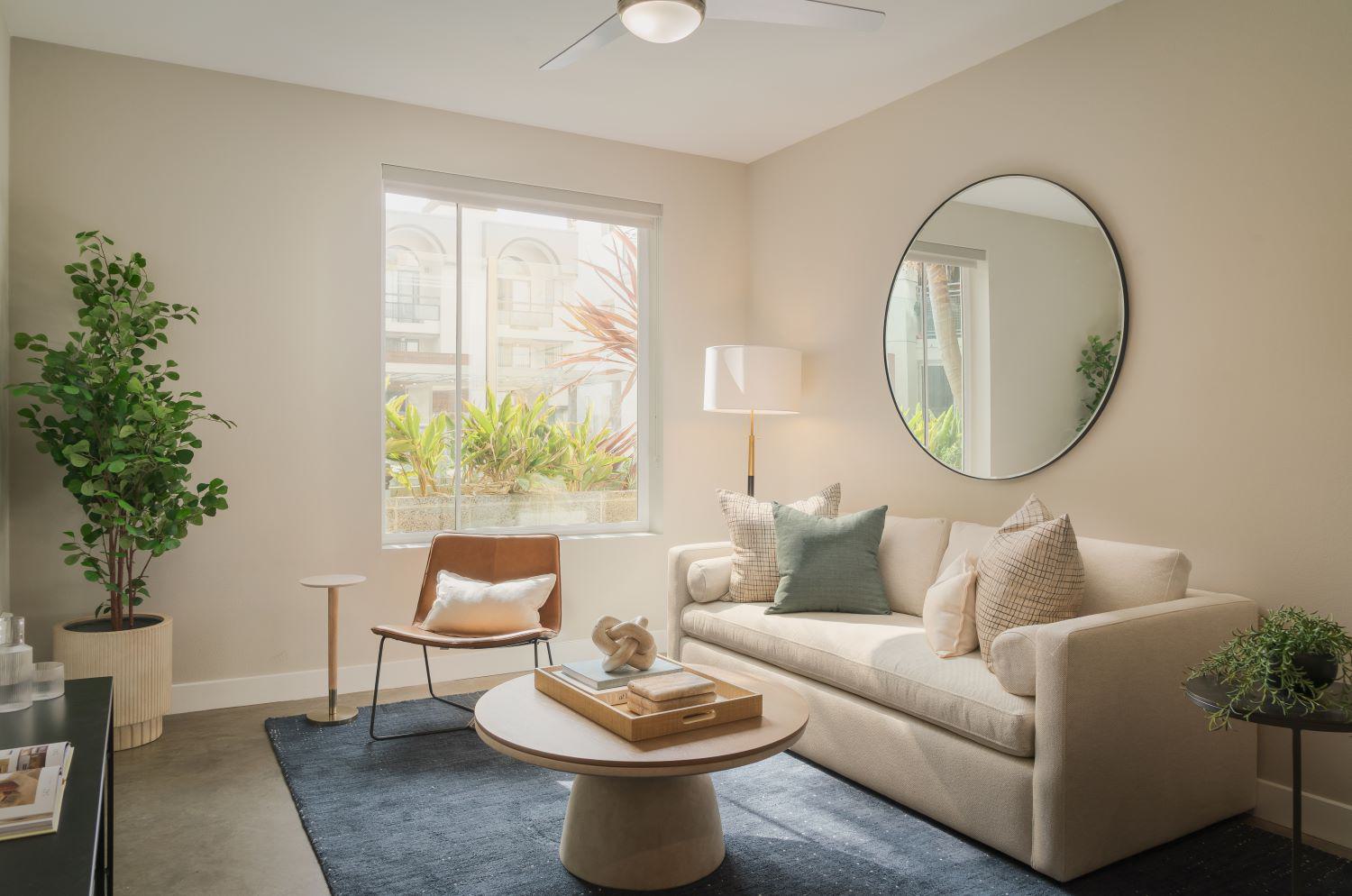 Modern living room scene with a blue velvet sofa, soft pillow, gold accent table, and potted plant.