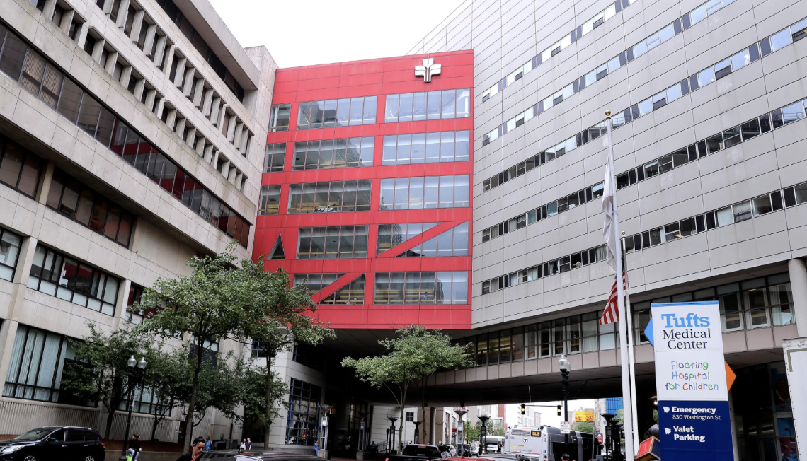 Exterior view of Tufts Medical Center in downtown Boston, featuring the red Floating Hospital for Children building and surrounding hospital complex.