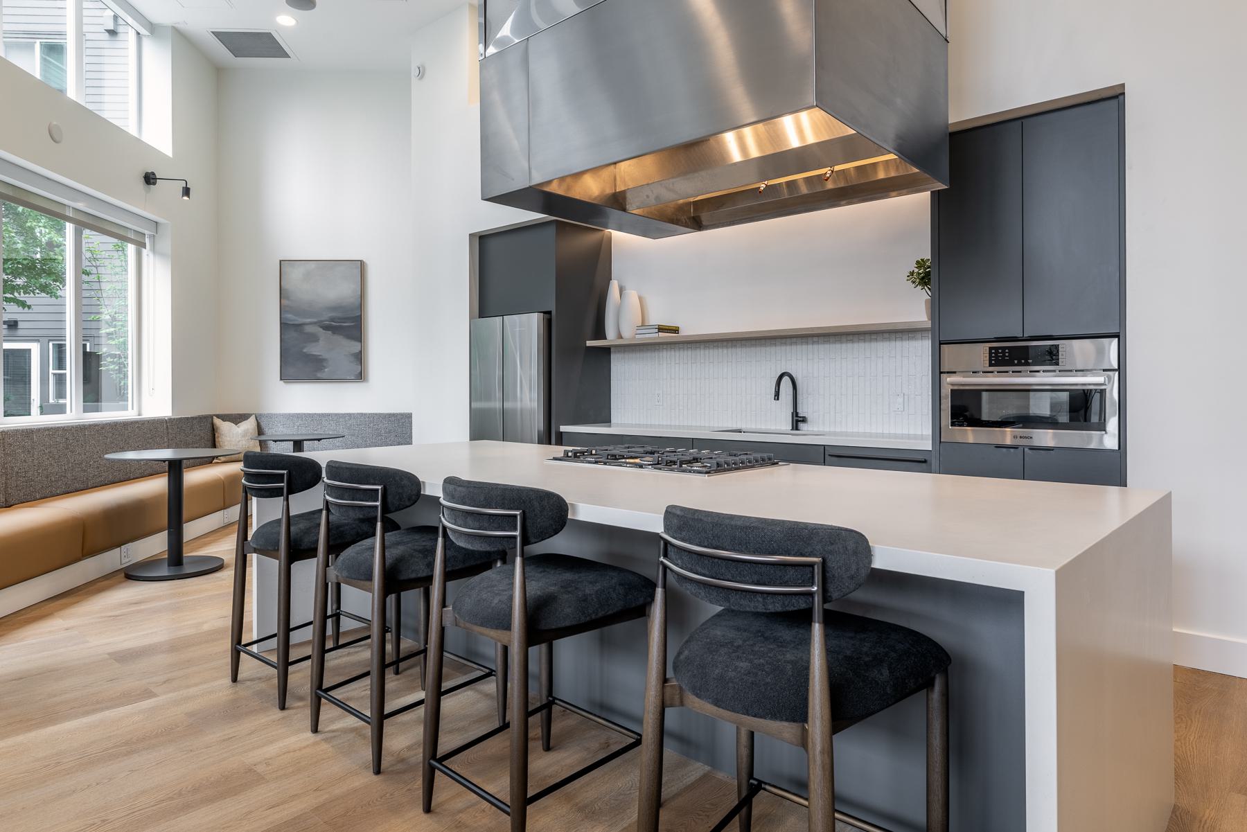 Modern resident lounge with cozy seating, a TV, and large windows opening to a furnished outdoor terrace.