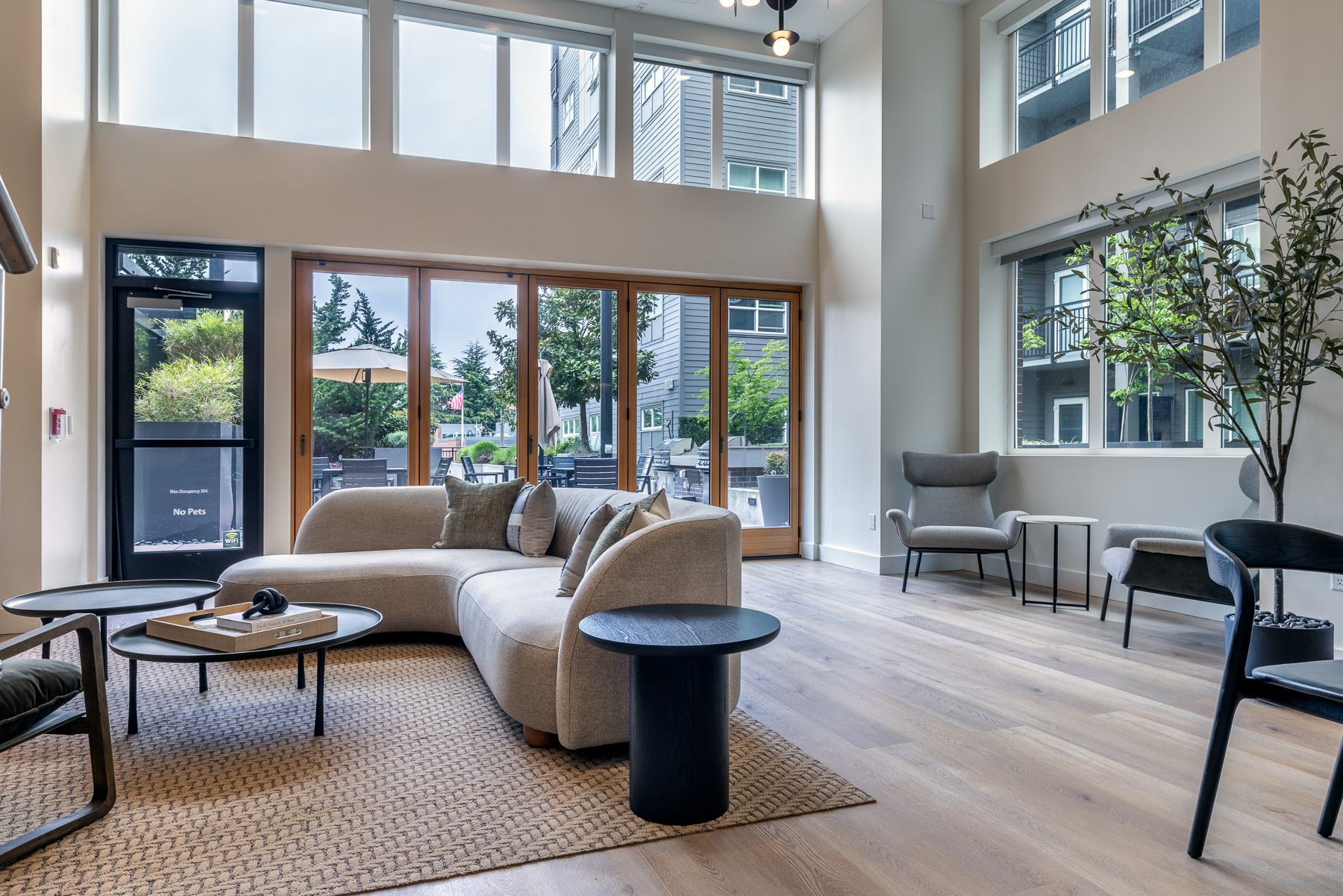 Outdoor courtyard lounge featuring a cozy brick fireplace, pergola overhead, and modern seating under warm evening lighting.