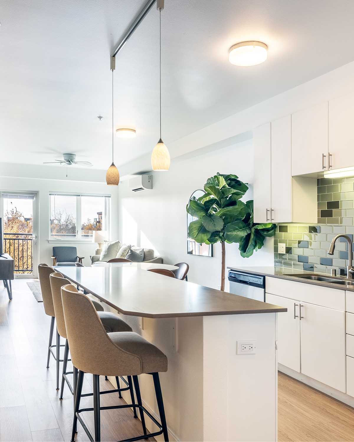 Modern apartment living room with neutral-toned furniture, large windows, and a private balcony.