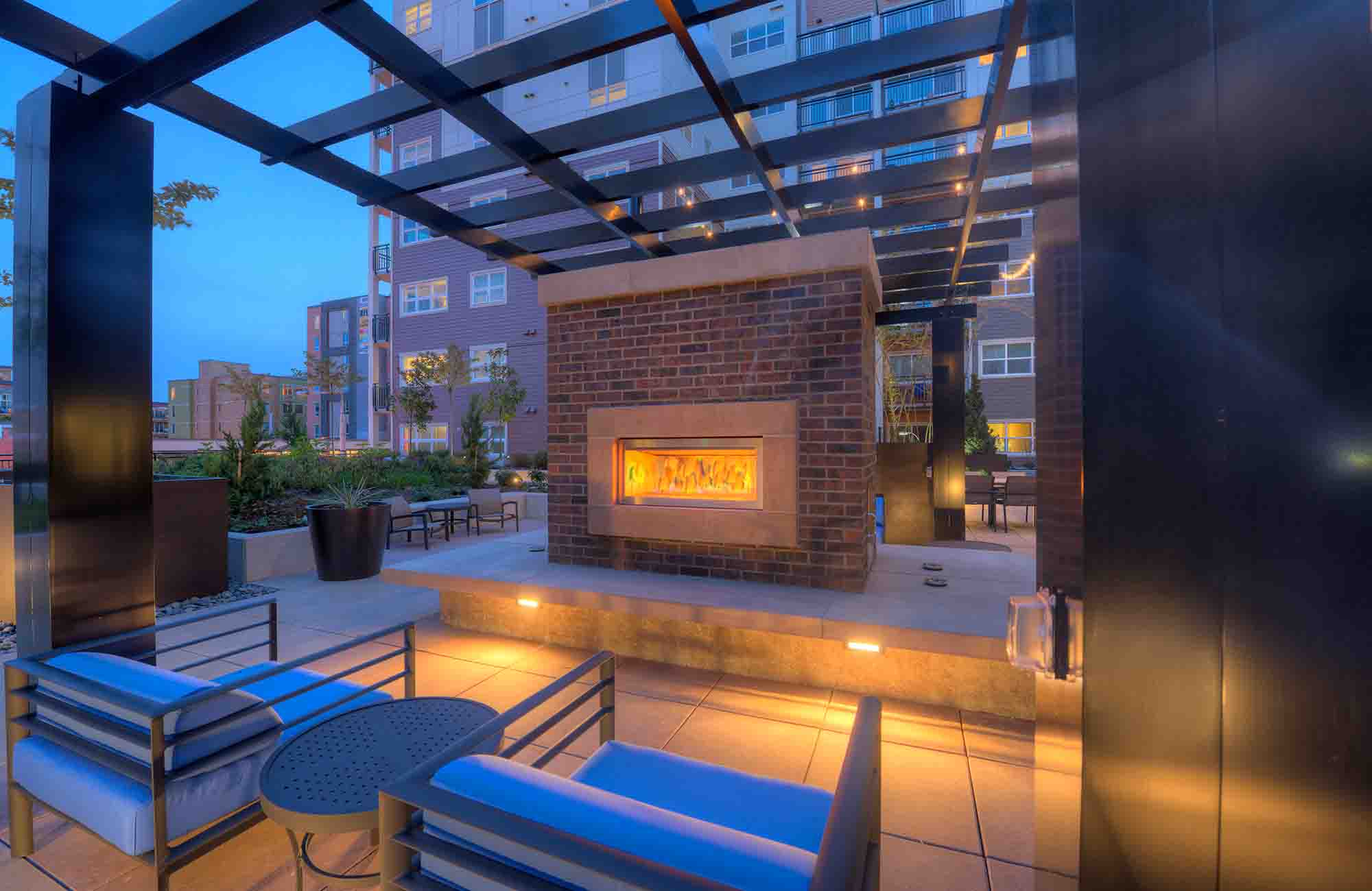 welcome outdoor courtyard at urbana apartments with comfortable lounge seating, lush planters, and a  a cozy outdoor fireplace