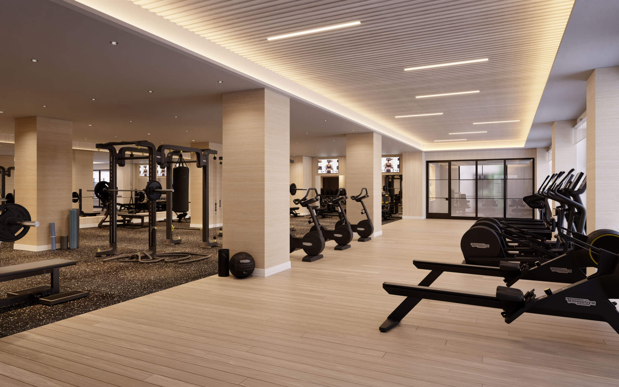 Spacious fitness center at Annex on 12th with high ceilings, wood-accented lighting, and separate zones featuring Technogym bikes, rowing machines, and strength equipment.