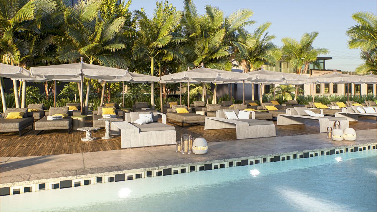 Poolside terrace with multiple daybeds and chaise lounges under gray umbrellas, surrounded by lush palm trees and tropical landscaping, with decorative lanterns placed throughout the deck area