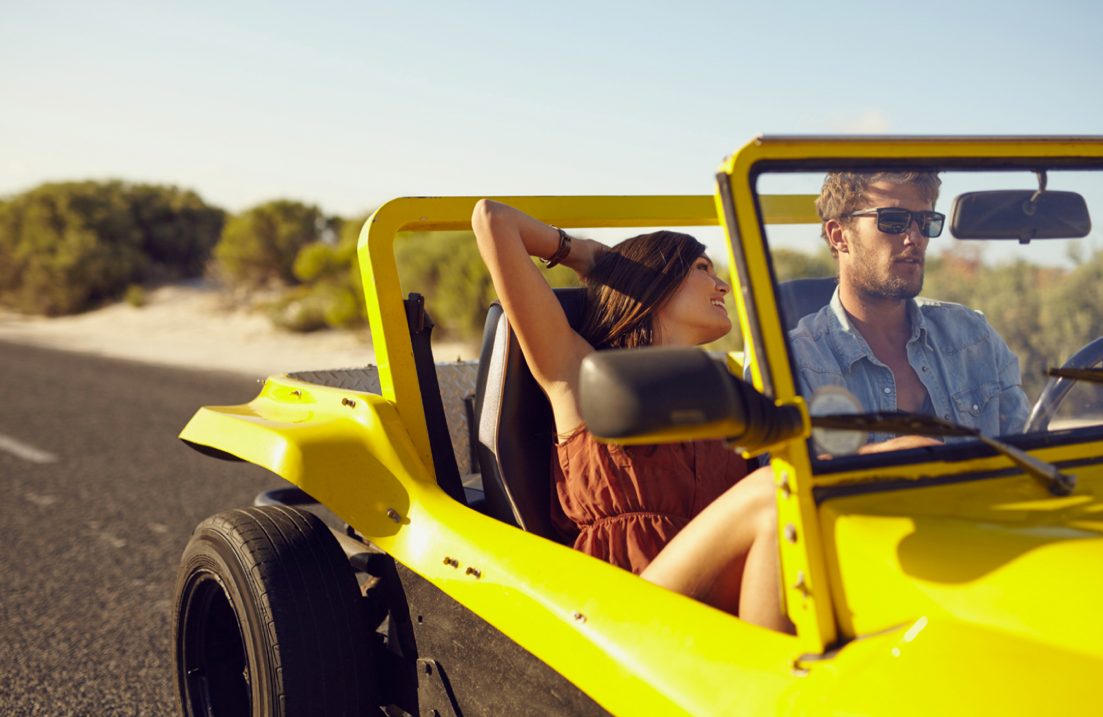 guy in sunglasses driving a girl with long hair in a dune buggy during a Bellevue Getaway - Hyde Square Apts