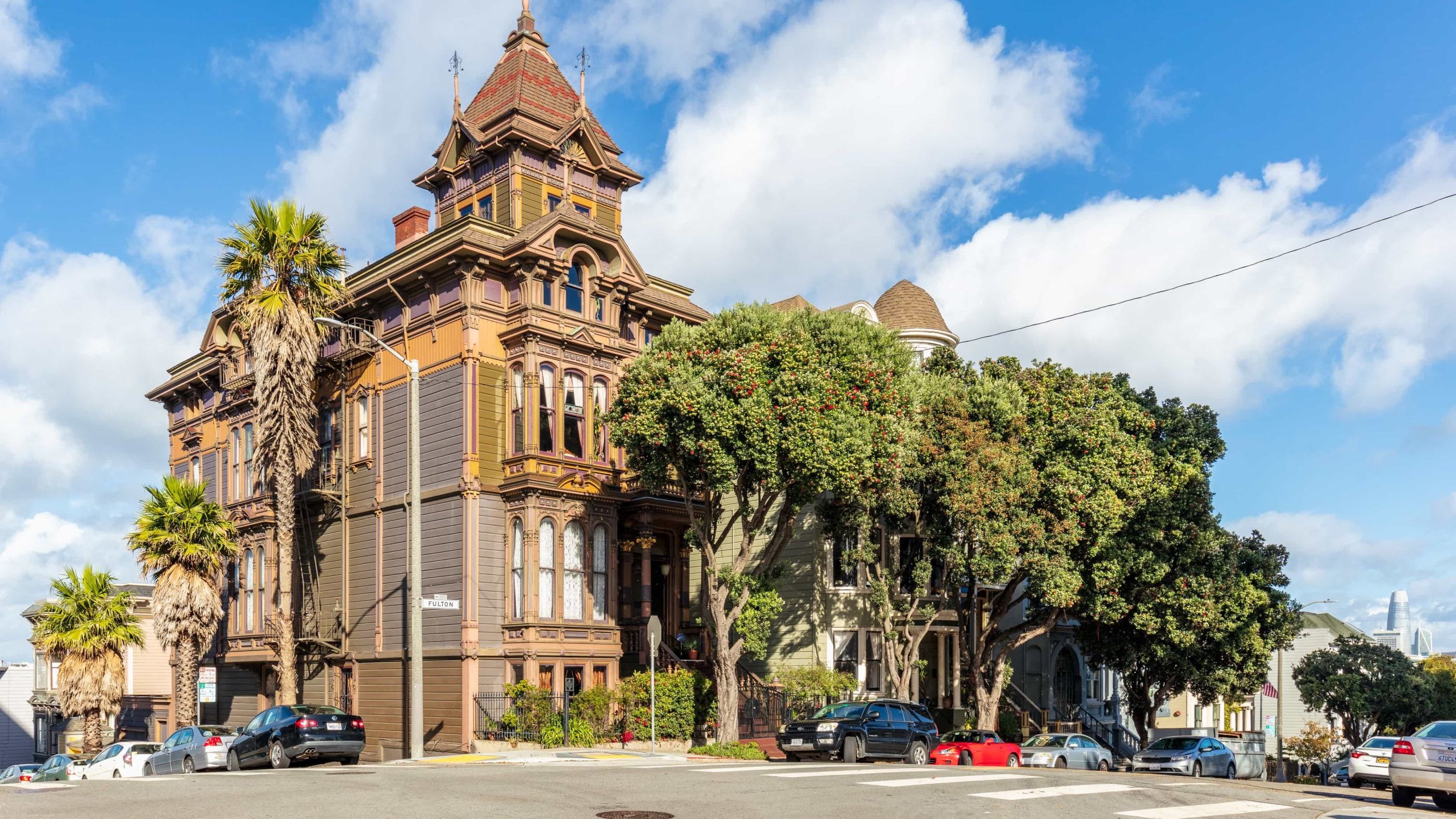 Historic Victorian house on Fulton Street in San Francisco, with ornate architecture, palm trees, and the Salesforce Tower visible in the distance.