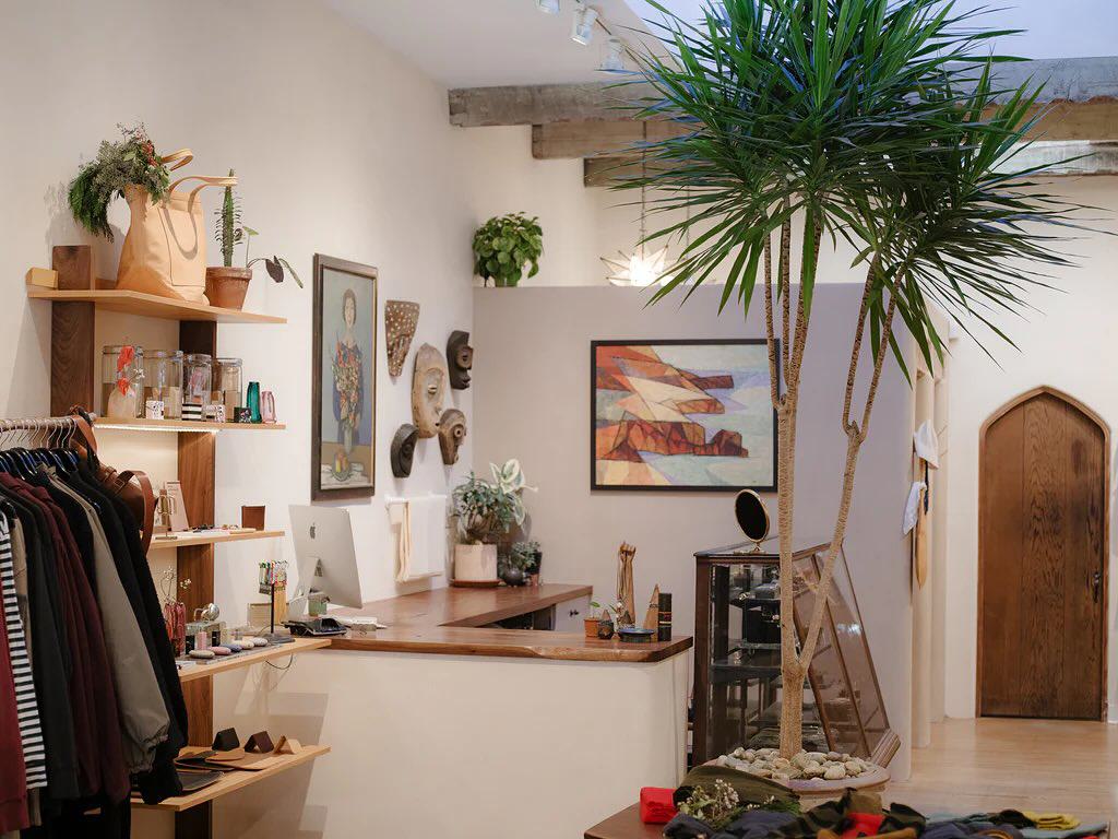 Inside Reliquary boutique on Hayes Street, with racks of clothing, shelves of accessories, eclectic artwork, and a tall indoor plant adding warmth to the space.