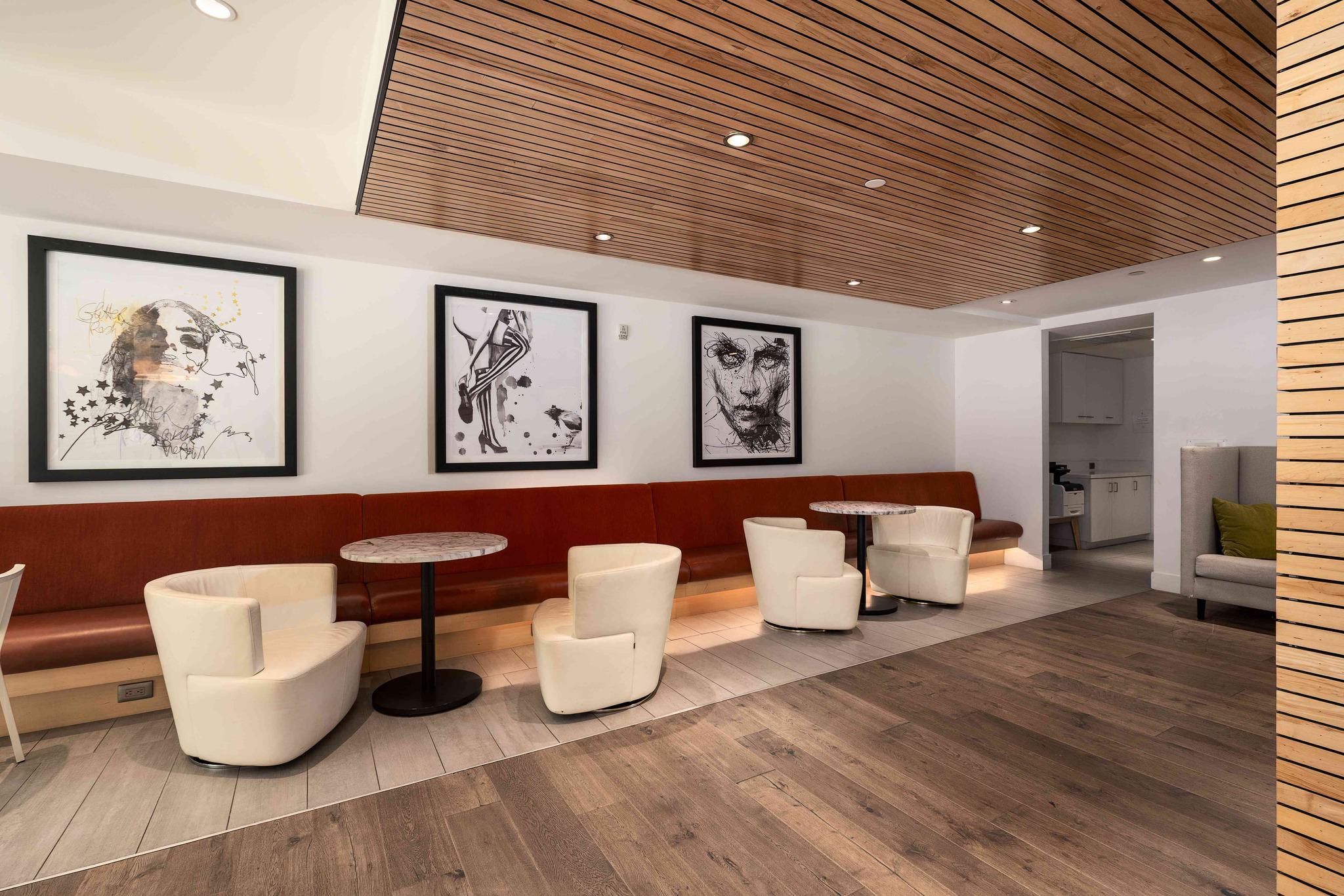 Café-style coworking area at Alchemy with banquette seating, round tables, and contemporary black-and-white artwork on the walls.
