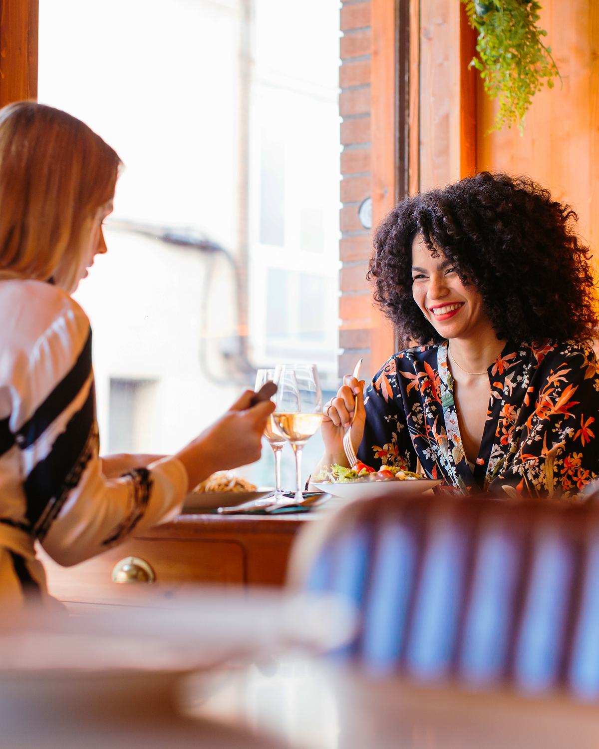 Two women enjoying lunch and wine together at a bright, cozy LA restaurant.