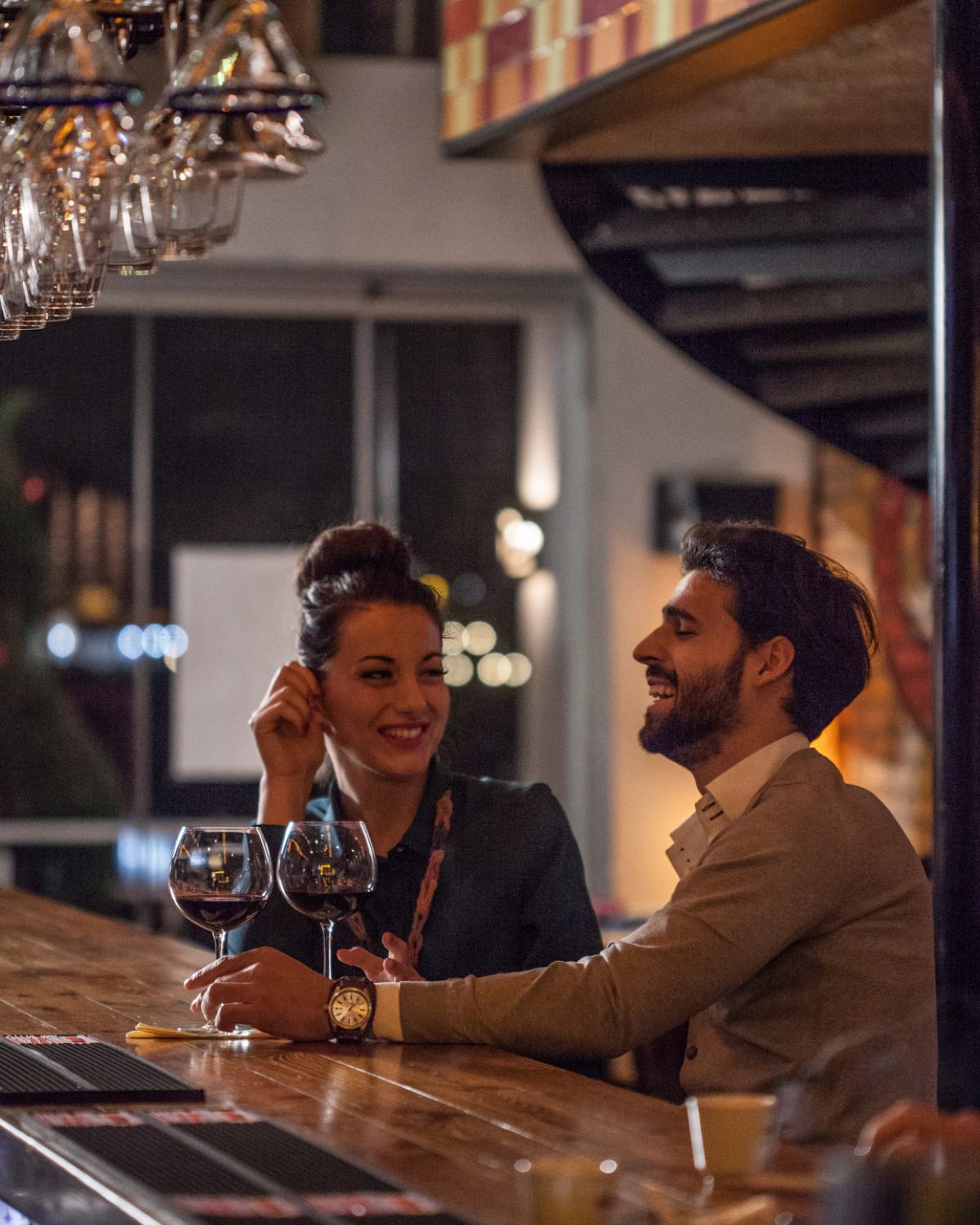 Couple enjoying wine and conversation at a cozy, dimly lit bar.