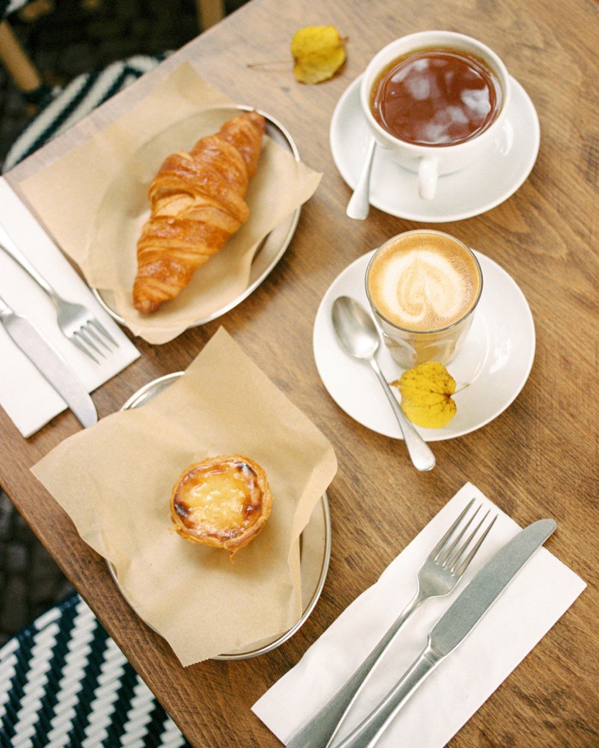 Café table with fresh croissants, a pastry, espresso, and tea, representing nearby coffee shops and casual dining options close to Latitude Apartments in Arlington, Virginia.