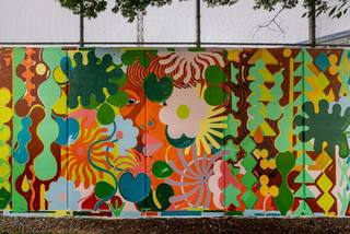 Colorful mural in NoMa featuring abstract floral patterns and a woman’s face surrounded by bold shapes and greenery.