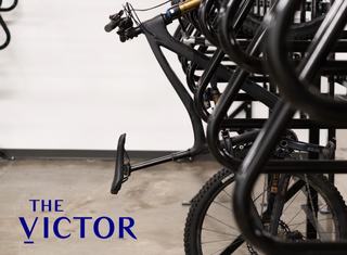 Close-up of a bike mounted in The Victor’s modern indoor bike storage room with organized black racks and concrete flooring, emphasizing convenient cycling access.