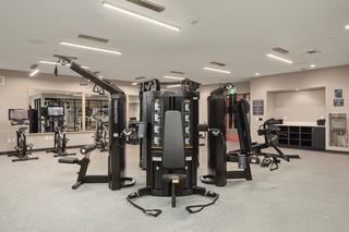 Modern fitness center at The Victor with treadmills, stationary bikes, strength-training machines, free weights, benches, and bright contemporary lighting.