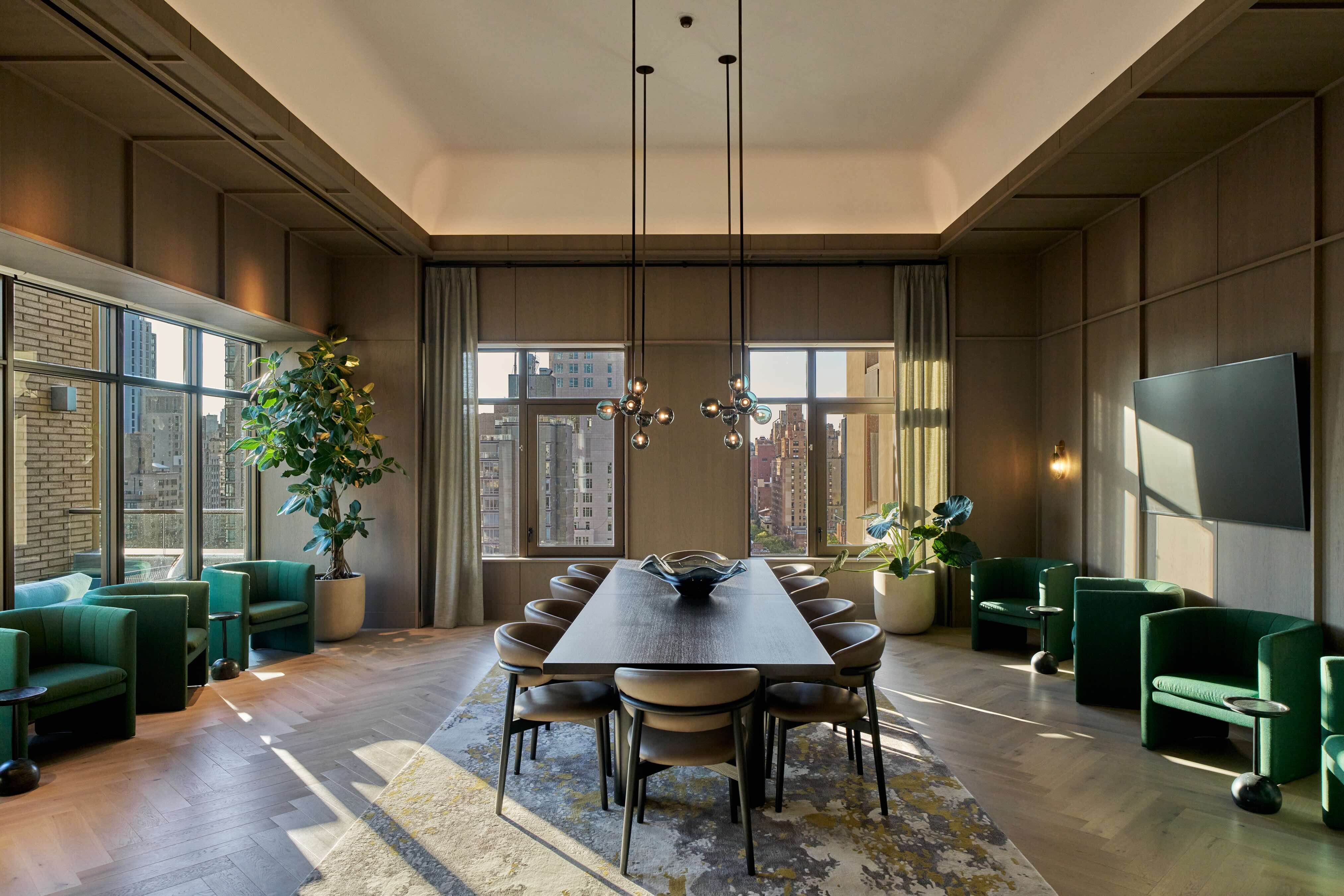 Private dining room at Maison 78 with a long dark table, upholstered chairs, green lounge chairs by the windows, and Upper East Side city views.