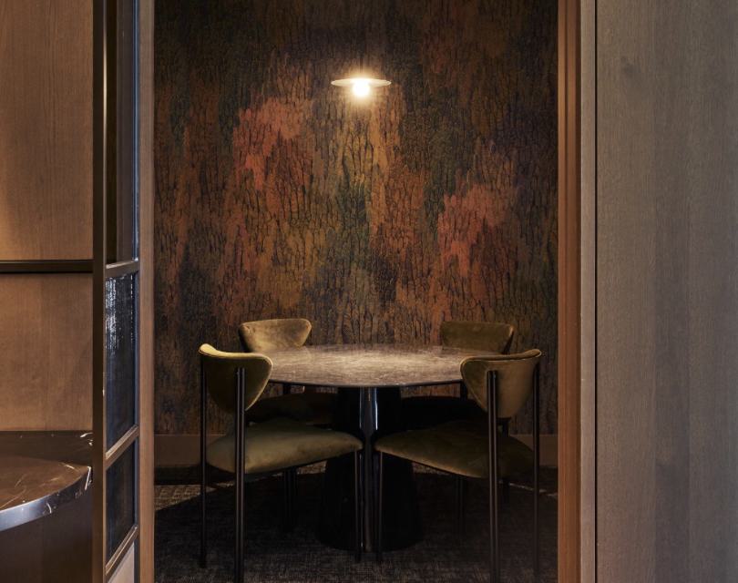 Private meeting room at Maison 78 with a round stone table, velvet chairs, warm pendant lighting, and richly textured wallpaper.