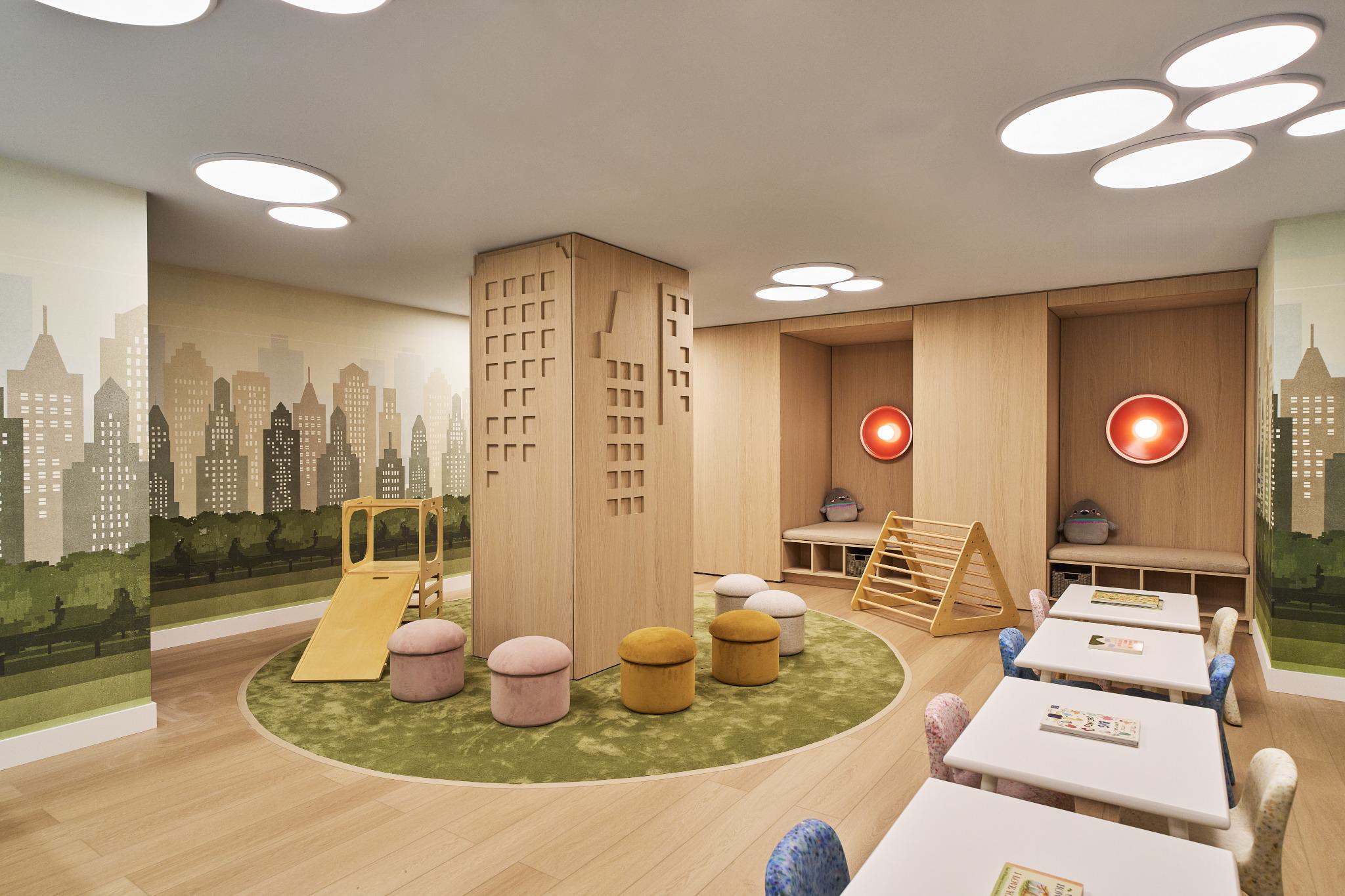 Children’s playroom at Maison 78 featuring a cityscape mural, circular green rug, climbing structures, soft stools, reading nooks, and small craft tables.