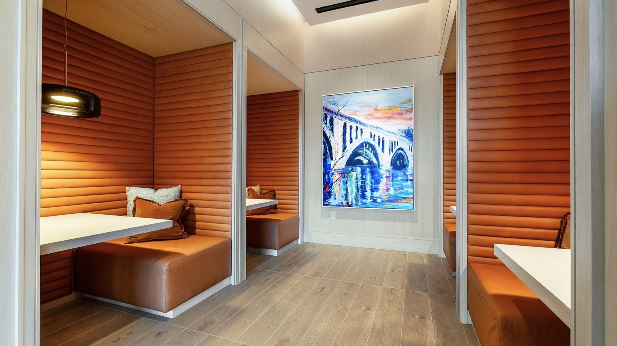 Cozy built-in work alcoves at Aerie featuring ribbed orange panels, benches, small tables, and individual task lighting.