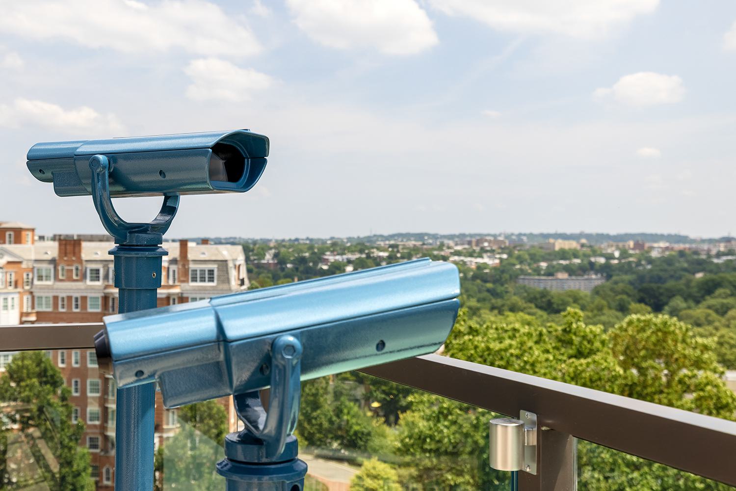  blue telescopes on Aerie’s observation deck overlooking the treetops, rooftops, and long skyline views across Woodley Park and Northwest DC.