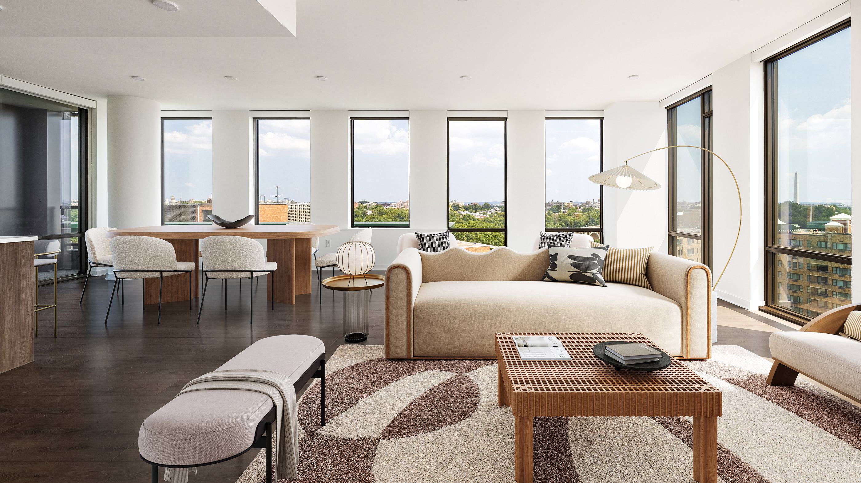 Bright, corner apartment living and dining area at Aerie with balcony, floor-to-ceiling windows overlooking treetops and city views, featuring a neutral sofa, curved dining table, and modern décor.