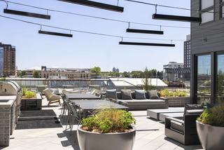 Forge’s clubhouse extends outdoors with grills, dining tables, and lounge seating set against RiNo’s industrial views and the Denver skyline.