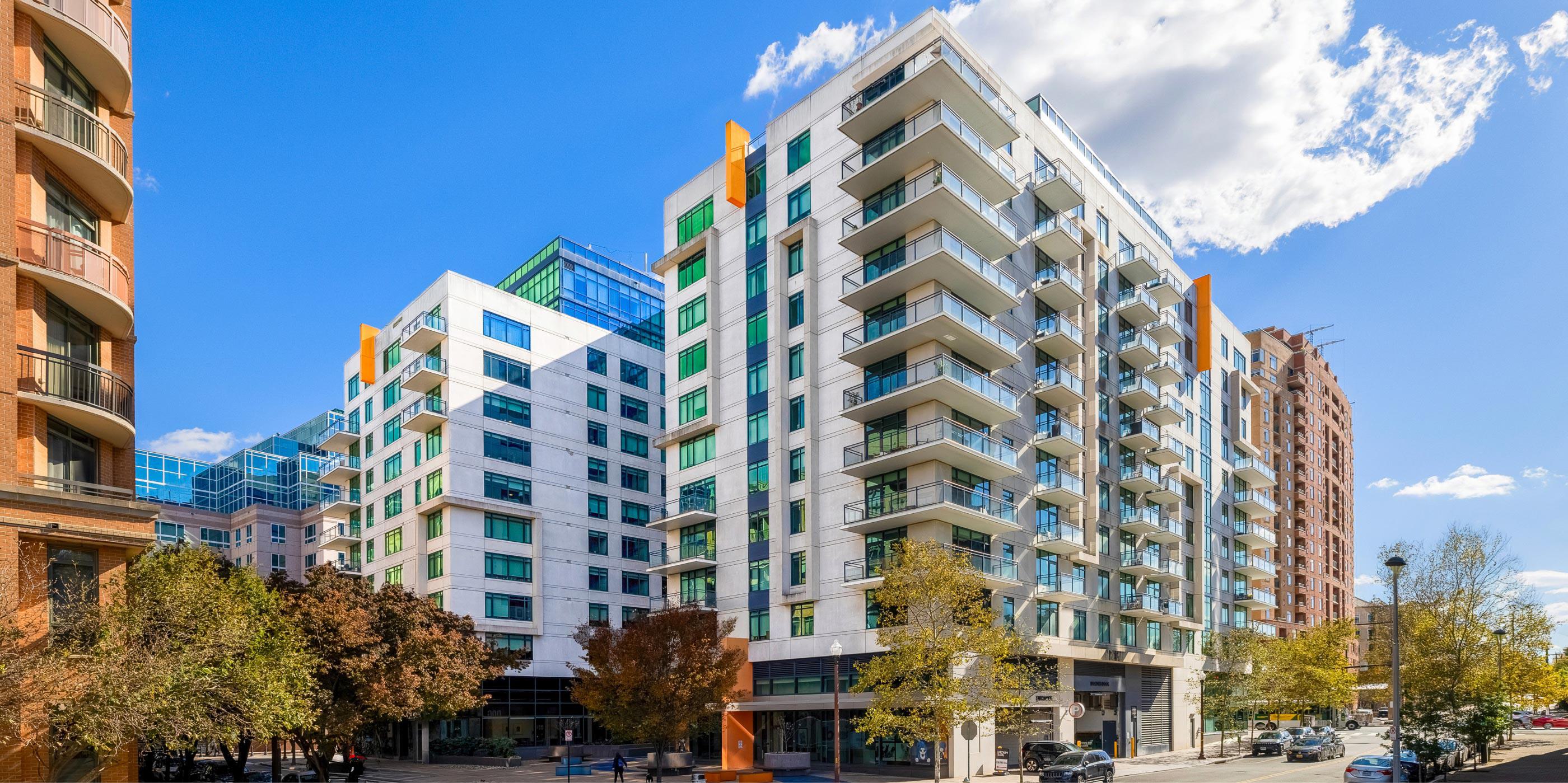 Exterior view of Latitude Apartments in Virginia Square showcasing modern architecture, glass balconies, street-level retail, and surrounding Arlington neighborhood.