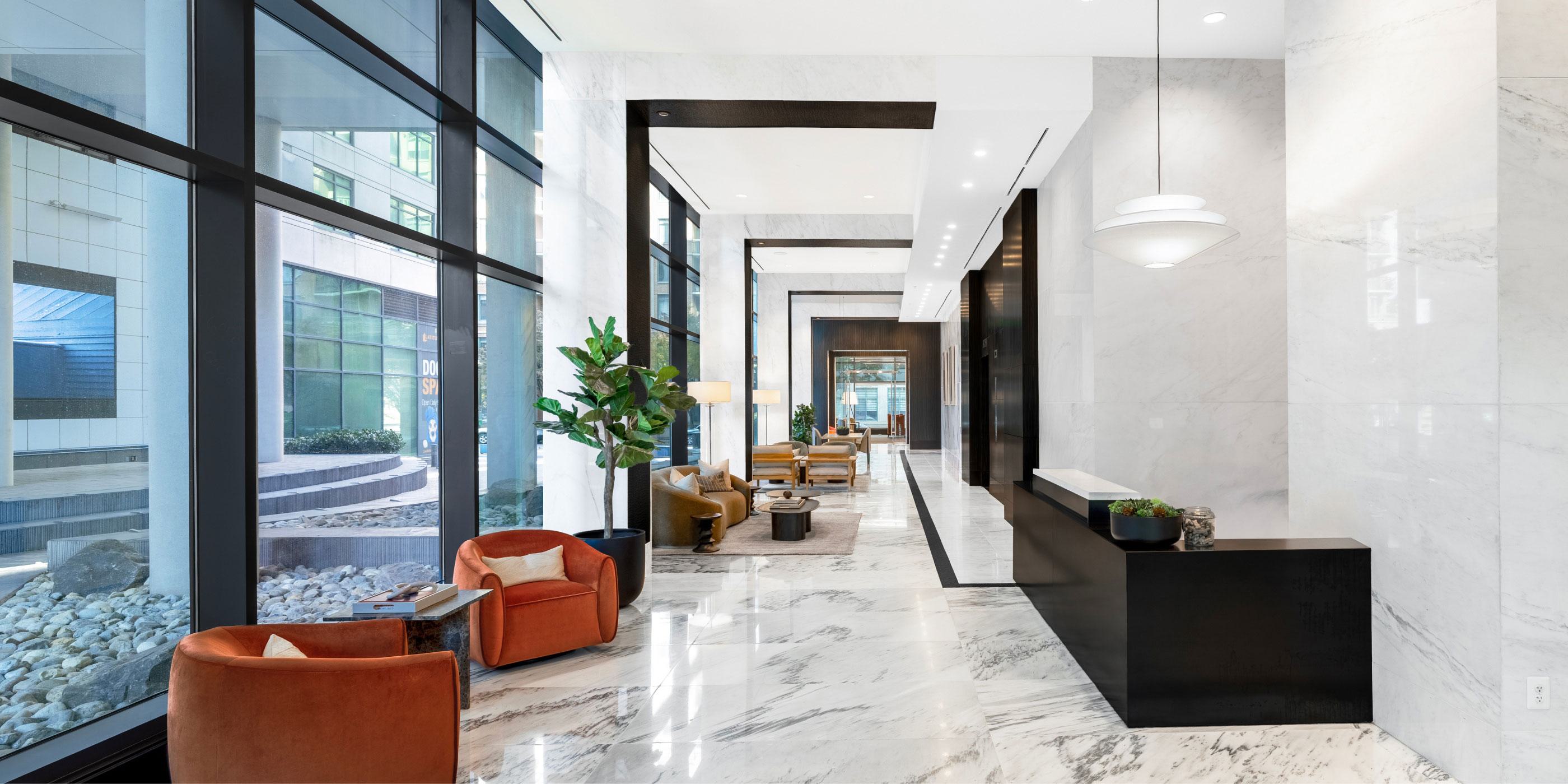 Sunlit lobby at Latitude Apartments in Virginia Square featuring modern lounge seating, marble floors, floor-to-ceiling windows, and a refined contemporary design.