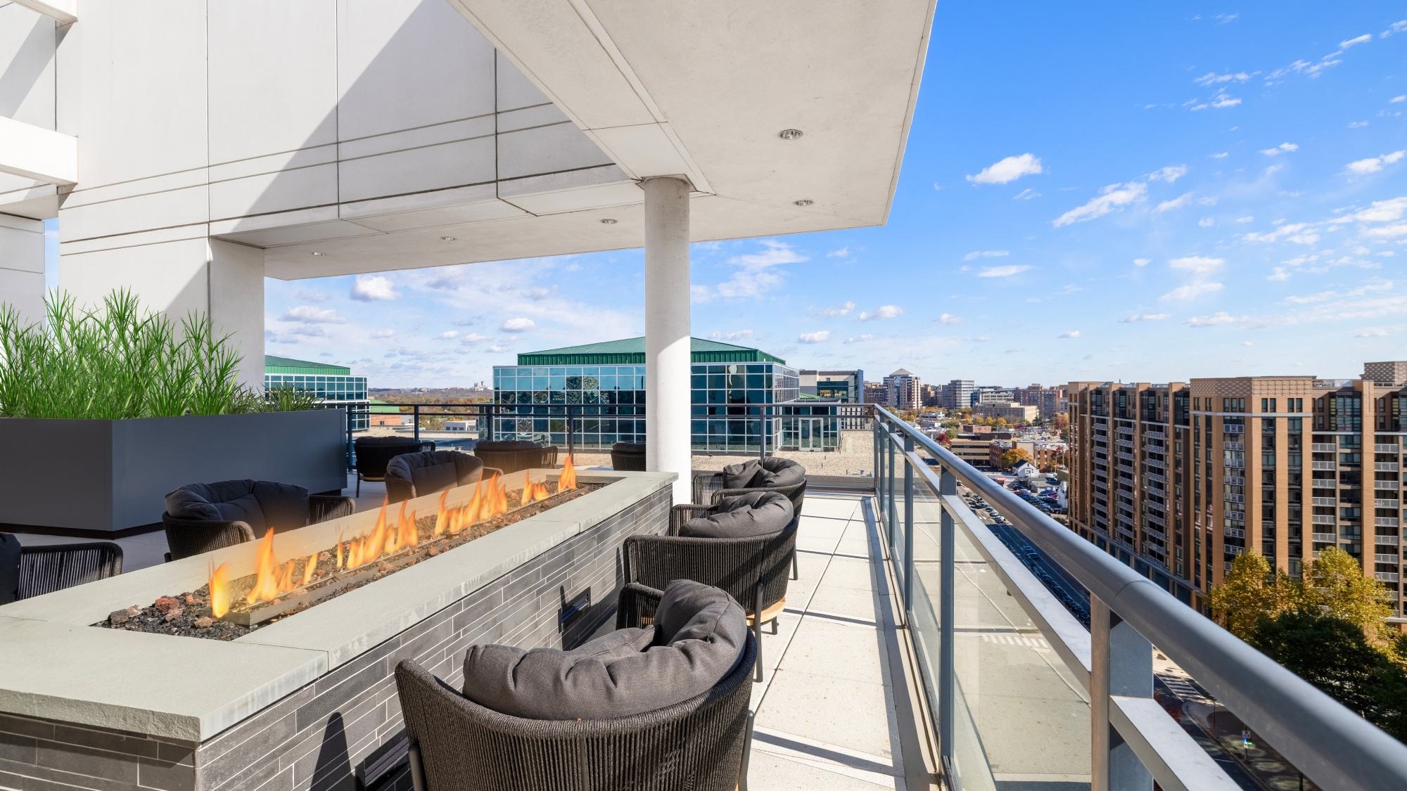 Latitude rooftop terrace with fire pit seating, glass railings, and expansive city views overlooking Arlington and the surrounding skyline.
