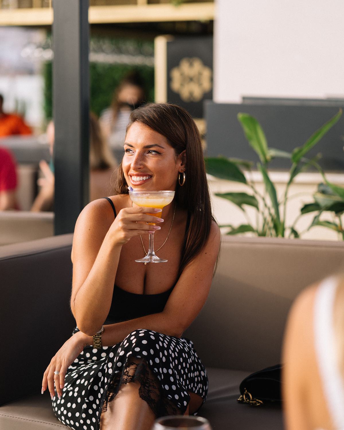 Woman on rooftop bar sipping a cocktail