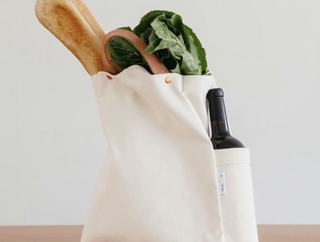 cloth grocery bag with a bottle of red wine, produce, and baguette