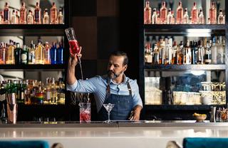 bartender artfully pouring a mixed drink into a glass