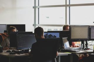 focused workers at workstations in an open floor plan near huge windows