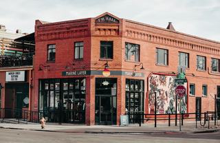 RiNo Denver corner building with brick façade, street mural, and ground-floor retail at 27th and Larimer.