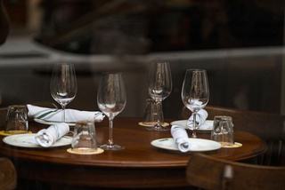 Set dining table with wine glasses, rolled napkins, and place settings inside a restaurant.