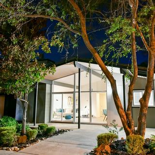 building exterior of arbors single family home - mid century modern with huge windows illuminated at dusk