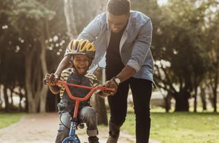 man teaching son to ride a bike