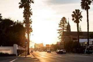 Sunset view along a palm-lined Los Angeles street near Sony Pictures Studios, with light traffic, low-rise buildings, and warm evening light.