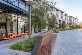 The Linear Green at Asher in Fremont, California, featuring a landscaped pedestrian walkway with seating, outdoor café tables, and modern apartment buildings along the path.