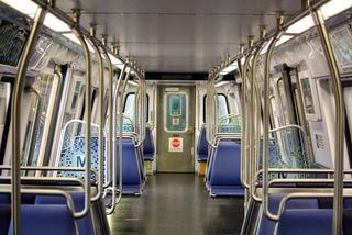 Interior of a Washington Metro rail car with blue seats, stainless steel poles, and an empty aisle, typical of trains used on the Silver Line and other WMATA lines.