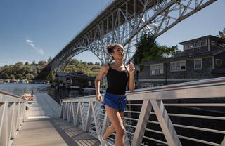 Runner on the Burke-Gilman Trail near Fremont, Seattle, with the Fremont Bridge and Lake Union houseboats in the background.