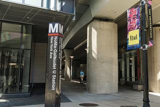 Entrance to the NoMa–Gallaudet U Metro station in Washington, DC, with station signage, concrete columns, and colorful NoMa street banners beneath an elevated structure.