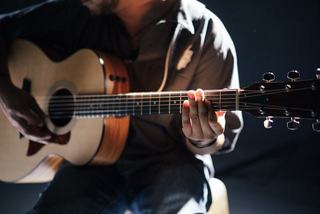 close up of a person playing acoustic guitar