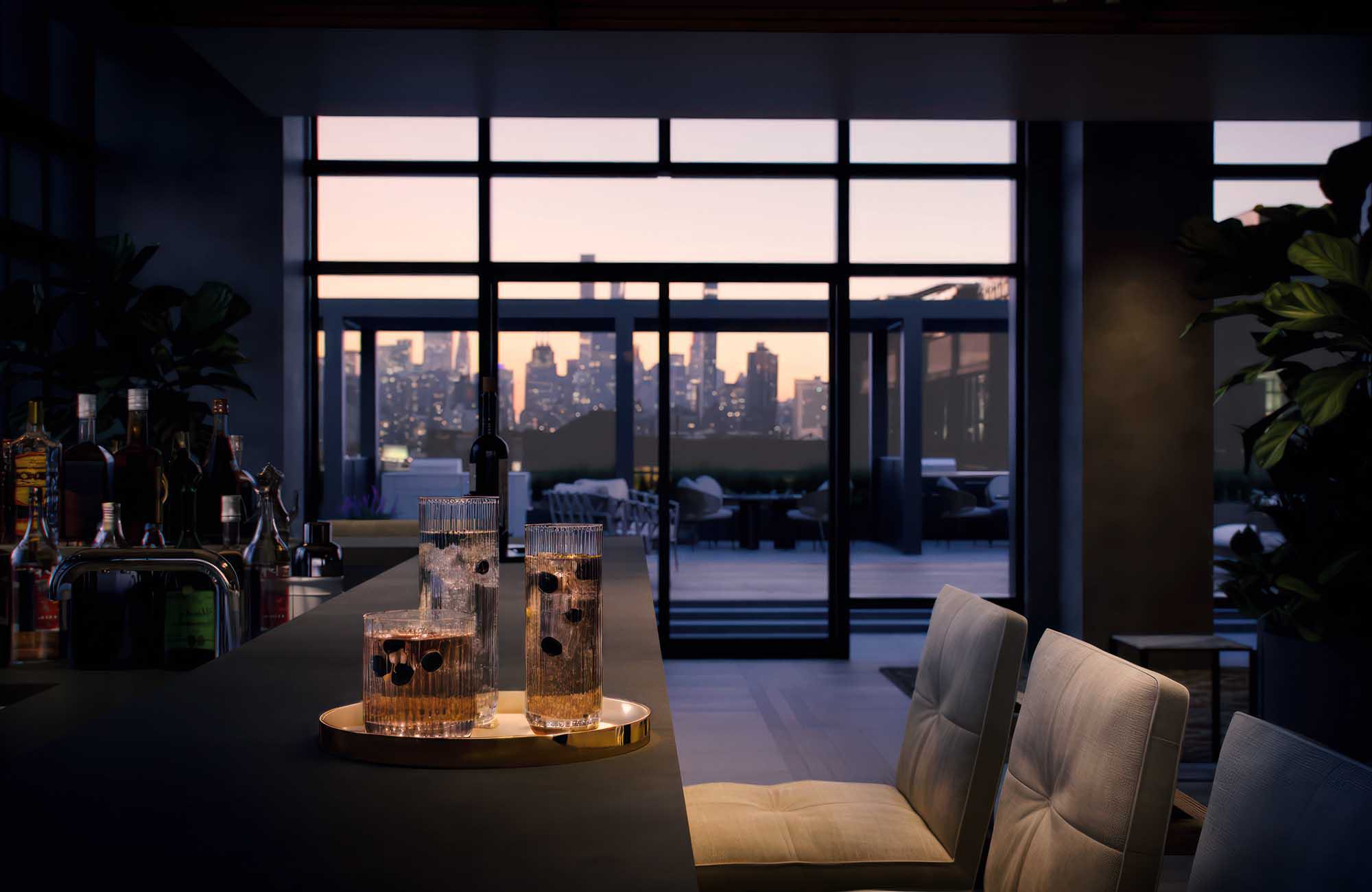 Evening view of Lumen’s resident lounge bar with upholstered seating, a stone countertop, and glassware set against floor-to-ceiling windows opening to a rooftop terrace and Manhattan skyline at sunset.