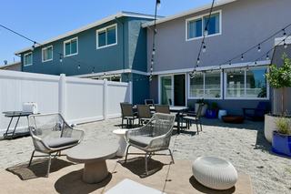 Private walled backyard at Admiral’s Cove townhome with patio seating, string lights, privacy walls, and an outdoor storage shed, offering a secluded outdoor living space.