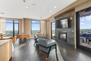 Indoor rooftop lounge at Vela in downtown Stamford with fireplace, media wall, lounge seating, and floor-to-ceiling windows overlooking the city