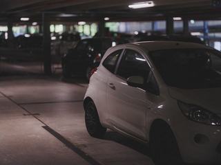 white compact car in a parking garage, representing the on-site parking garage at vela in downtown stamford