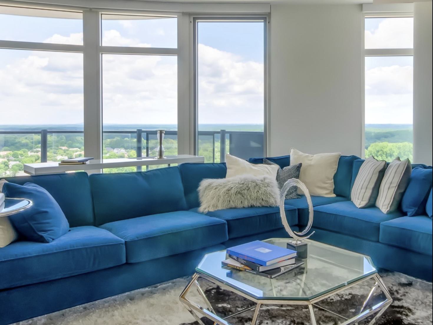high-rise apartment living room with huge windows and green canopy views