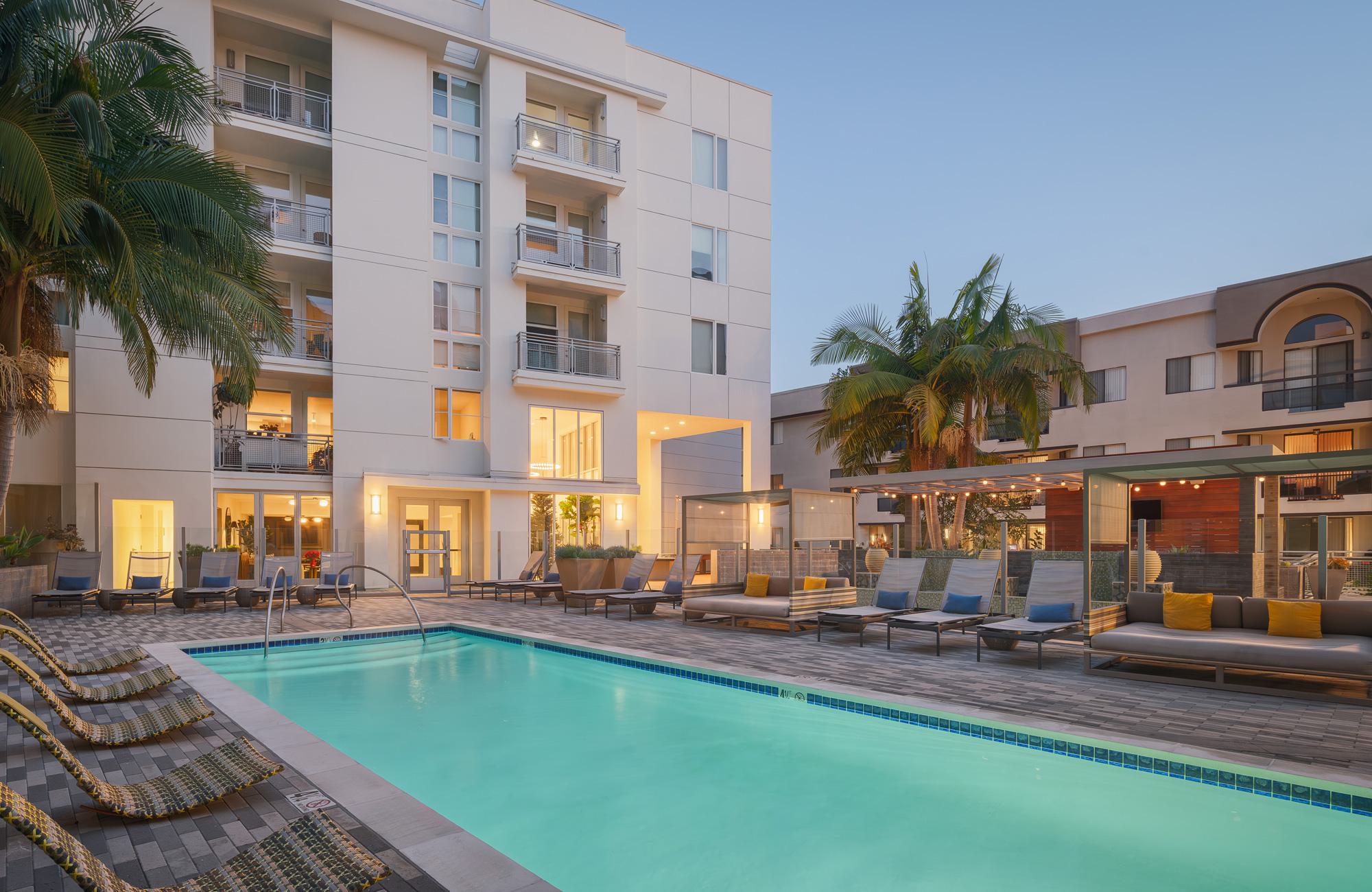 Evening view of Desmond’s courtyard pool with lounge seating, cabanas, and palm trees.