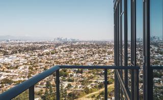 High-rise balcony at ARQ overlooking West Adams and Culver City with a clear view toward the Downtown Los Angeles skyline in the distance
